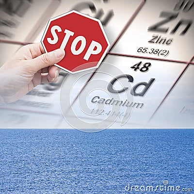 Stop pollution from dangerous cadmium and heavy metals in seawater - concept with hand holding a stop sign against a cadmium Stock Photo