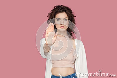 Stop. Portrait of serious beautiful brunette young woman with curly hairstyle in casual style standing with stop hands gesture and Stock Photo