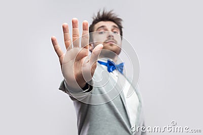Stop. Portrait of serious handsome bearded man in casual grey suit, blue bow tie standing with rejecting stop hand and try to Stock Photo