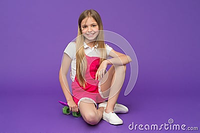 Stop and relax. Kid girl relax sits penny board. Modern youth hobby. Girl happy face sitting on penny board violet Stock Photo