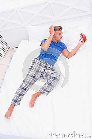 Stop ringing. Lethargic male awake with alarm clock. early morning. sleepy man in bedroom. no energy and relax Stock Photo