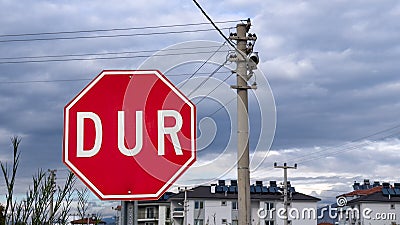Stop road sign in Turkish - DUR - on a cloudy day next to an electric pole Stock Photo