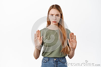 Stop. Serious girl raising hands to block, say no, disapprove action and refusing something bad, frowning displeased Stock Photo