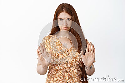 Stop it. Serious redhead girl shows prohibit gesture, raising hands to say no, forbid or refuse something, stay back Stock Photo