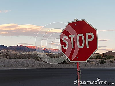 Stop Sign with Sunset Background over Desert Mountains Stock Photo