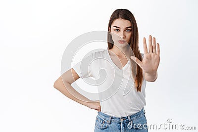 Stop, stay back. Serious and confident girl stretch hand to say no, prohibit, keep social distancing on pandemic, making Stock Photo