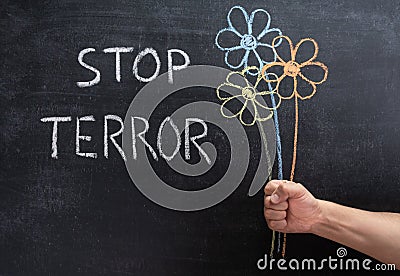 STOP TERROR on a chalkboard, three flowers drawn in chalk in a man`s hand Stock Photo