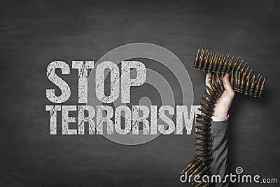 Stop terrorism text on blackboard with businessman hand holding ammunition Stock Photo