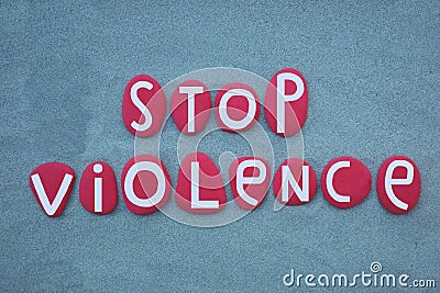 Stop violence, pacifist slogan composed with red colored stone letters over green sand Stock Photo