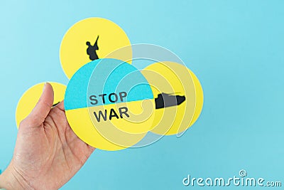 STOP WAR. Circle with Ukrainian flag and Stop war message on one hand. Silhouette background of soldier and war tank on blue Editorial Stock Photo