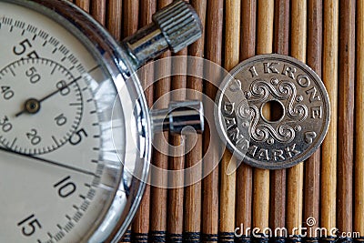 Stopwatch and coin with a denomination of 1 danish krone cents on wooden table background Stock Photo