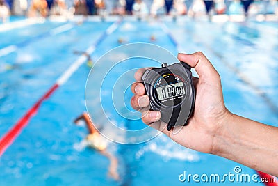 Stopwatch holding on hand with competitions of swimming. Stock Photo
