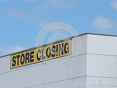 Store Closing black on yellow letters on a white claded industrial building Stock Photo