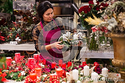 Store employee makes Christmas composition with candles Stock Photo