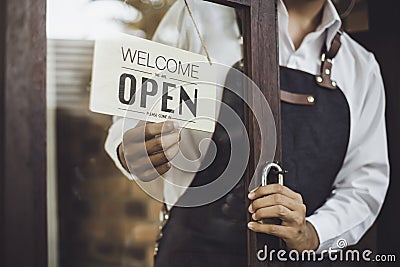 Store owner turning open sign broad through the door glass Stock Photo