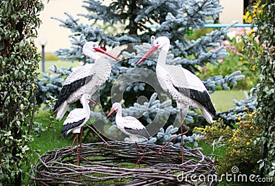 Stork family with four baby storks in a garden. Garden figurine. Stock Photo