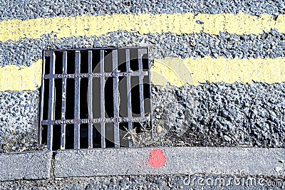 Storm Drain Grill and Double Yellow Painted Lines Editorial Stock Photo