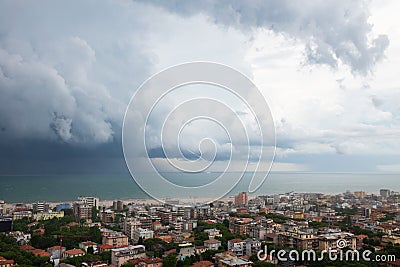 Storm with tornado in Rimini, Italy. Picturesque landscape view with sea, clouds, cityscape and whirlwind. Stock Photo