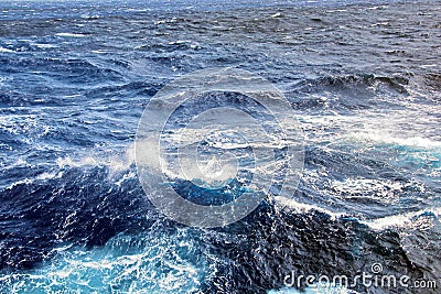 Storm waves in the world ocean. Kind of waves, crests, splashes, foam against the background of the sea and blue sky. Stock Photo