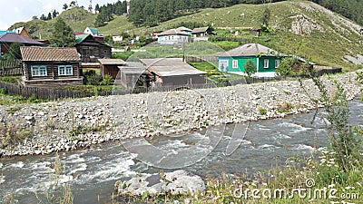 A stormy river and bright wooden rural houses in the Altai. Summer trip to Siberia in Russia Stock Photo