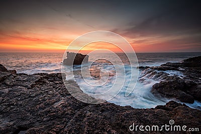 Fiery sunrise sky at a rocky coastline Stock Photo