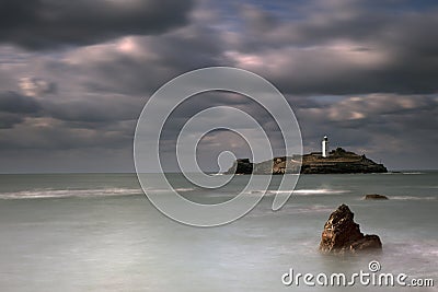 Stormy skies over Godrevy Lighthouse on Godrevy Island in St Ives Bay with the beach and rocks in foreground, Cornwall uk Stock Photo