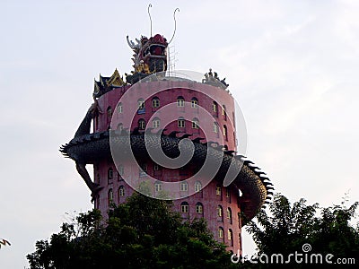 17-story tall pink cylindrical temple with a gigantic red and green dragon sculpture that curls across the entire height Editorial Stock Photo