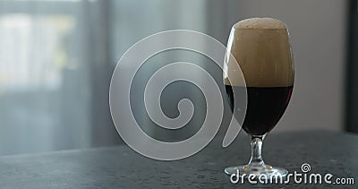 Stout beer drops slide from tulip glass on terrazzo countertop with copy space Stock Photo