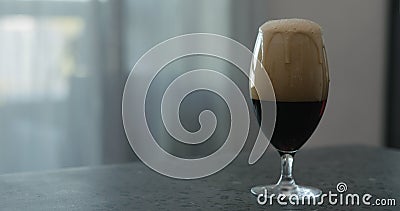 Stout beer drops slide from tulip glass on terrazzo countertop with copy space Stock Photo