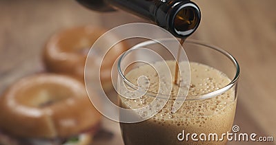 Stout beer poring into glass with bagels on background Stock Photo
