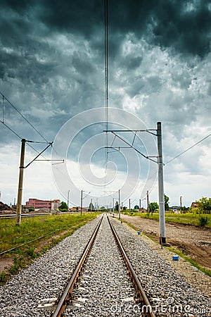 Straight railroad with dark cloudy sky Stock Photo
