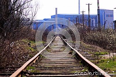 Straight railroad going to old blue factory Stock Photo