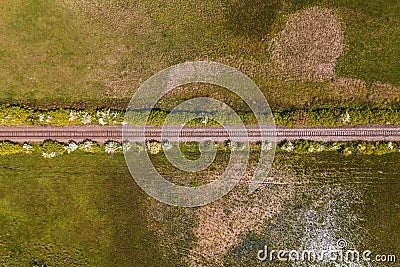 Straight railroad track through green countryside landscape in spring, drone pov Stock Photo