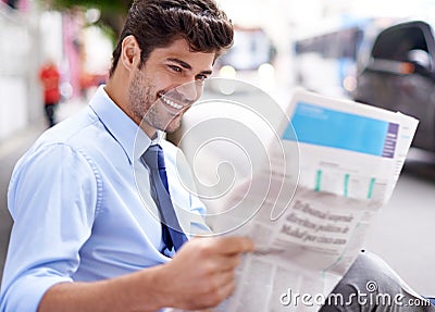 Straight to the business section. A handsome young businessman reading a newspaper while sitting on a bench in the city. Stock Photo