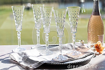 Straight on view of tall crystal flute glasses with a bottle of rose wine to the side, against a bright sunny window. Stock Photo