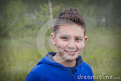 Straight on view of a young smiling boy outside in the forest Stock Photo