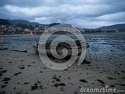 Stranded beached fishing boat vessle ship on coastline shore of seaside town village Combarro Galicia Spain at low tide Stock Photo