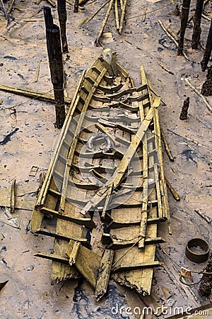 Stranded wreck of the little wooden boat with pieces of wood all around after storm Stock Photo