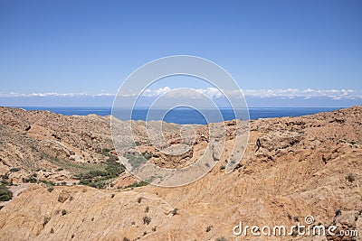 The strange formations of Skazka, or Fairytale Canyon in Kyrgyzstan with lake Issyk-Kul in the background Stock Photo