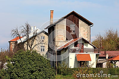 Strange looking tall abandoned old suburban family house with dilapidated facade and broken windows surrounded with other houses Stock Photo