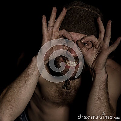 Strange Russian man with a naked torso and a woolen hat doing different signs with her hands Stock Photo