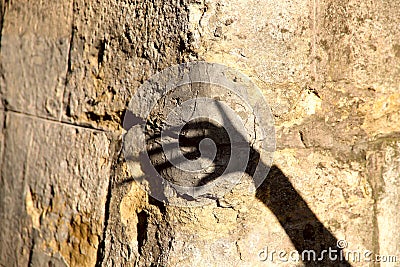 Strange shadow of one hand on an old stone wall. Black shadow, female hand Stock Photo