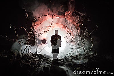 strange silhouette in a dark spooky forest at night, mystical landscape surreal lights with creepy man. Toned Stock Photo