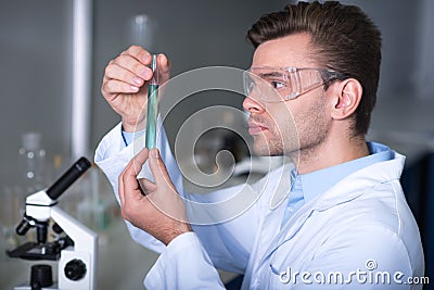 Young handsome explorer keeping and overlooking test tube. Stock Photo