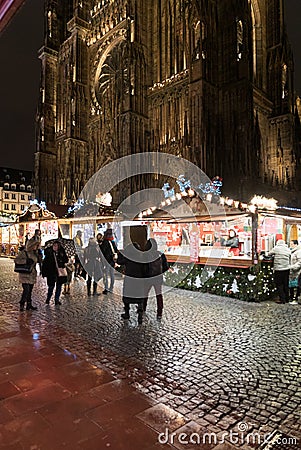 Nightime view of many people visiting the famous Christmas market in Strasbourg with the cathedral in the background Editorial Stock Photo