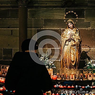Woman light candles in Strasbourg, France Notre-Dame cathedral Editorial Stock Photo