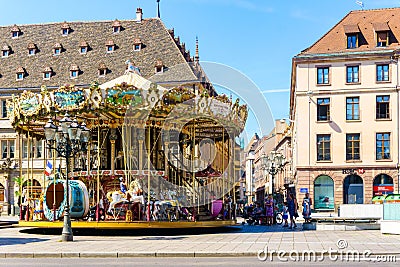 Old vintage carousel merry-go-round in the PLace Kleber, Strasbourg with people admiring the majestic attraction and the surround Editorial Stock Photo
