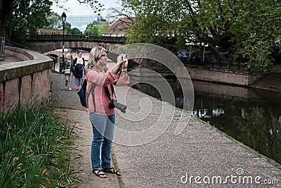 Portrait of tourist taking a photo with her smartphone in the street Editorial Stock Photo