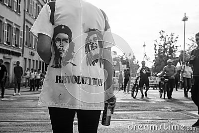 Portrait on back view of woman protesting in the street with the che guevara and bob marley portrait on shirt with text REVOLUTION Editorial Stock Photo