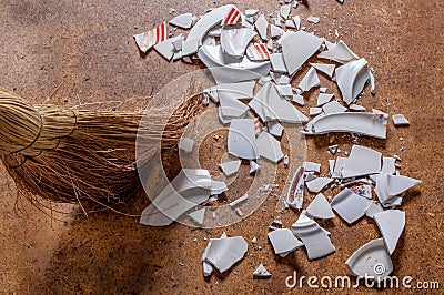 Pieces of shattered dishes. Fragments of the broken white ware on the floor. Stock Photo